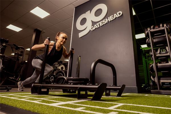 A woman pushing a weighted mechanism in a GO Gateshead gym