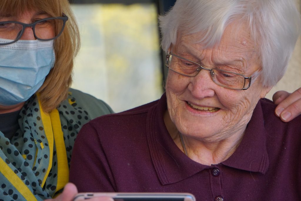 An image of a carer showing an elderly person something on her phone